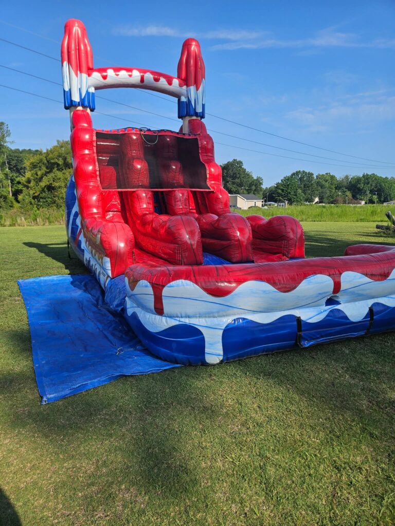 Red, white and blue dual lane water slide set up on grass