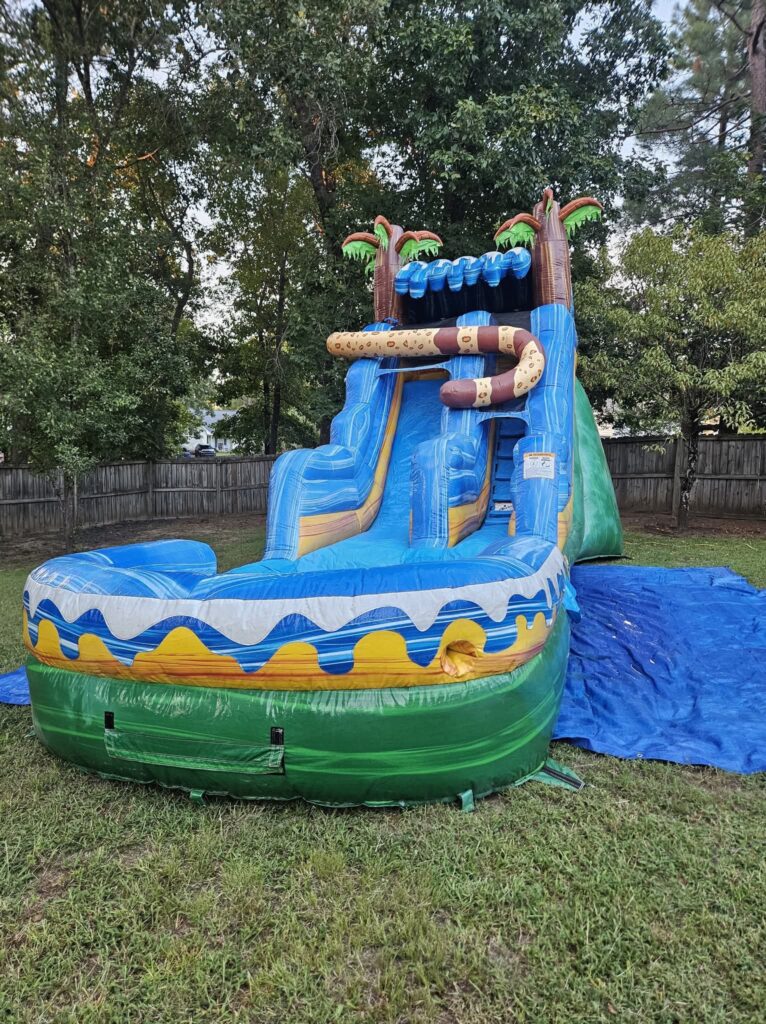 Blue and green water slide with palm trees and a splash pool