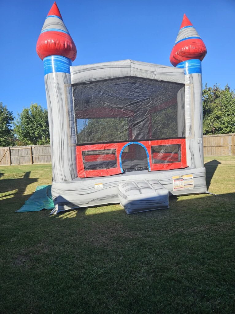 Grey marble-look castle bounce house set up on a lawn