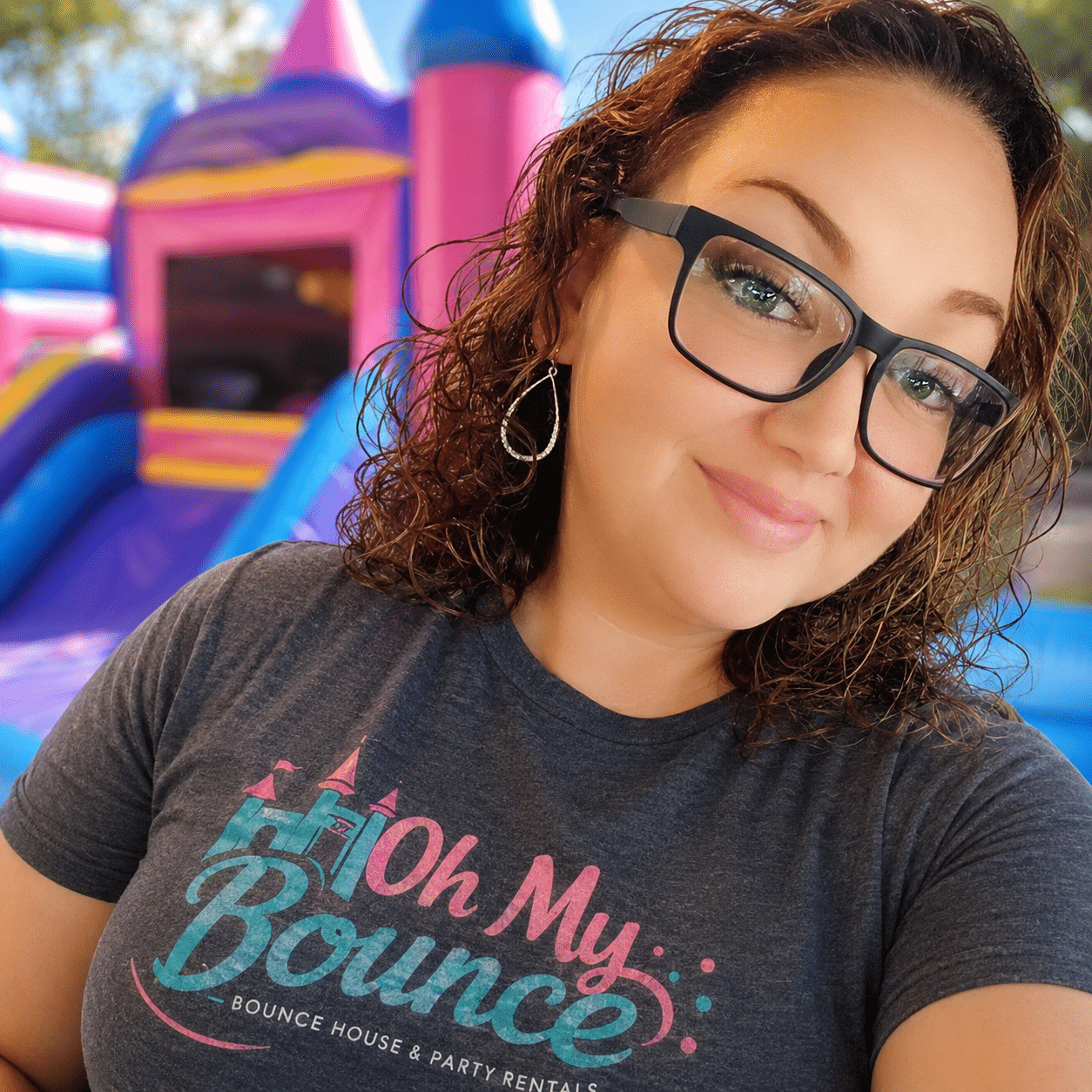 Vannessa, owner of Oh My Bounce, in an Oh My Bounce shirt in front of a bounce house